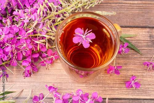 A drink  decoction  from the leaves and flowers of a useful plant of ivan-tea  kipreya  epilobium  in a transparent glass mug on a wooden background. Close-up. Phytotherapy  alternative medicine.