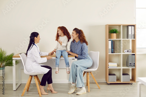 Treatment and diagnosis of neurological diseases. Doctor neuropathologist with special hammer checks knee reflexes on leg little girl. Mom and her little daughter at reception at pediatric neurologist
