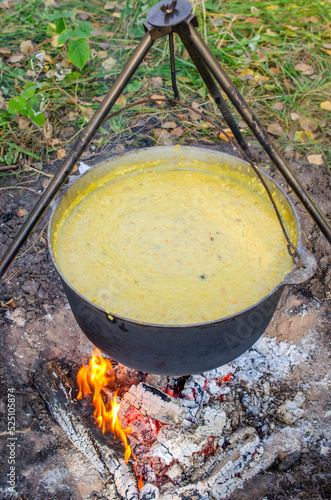 A cauldron in which kulesh is boiled hangs on a tripod over the fire
