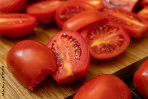 Tomatoes cut in half lie on a wooden board © potas