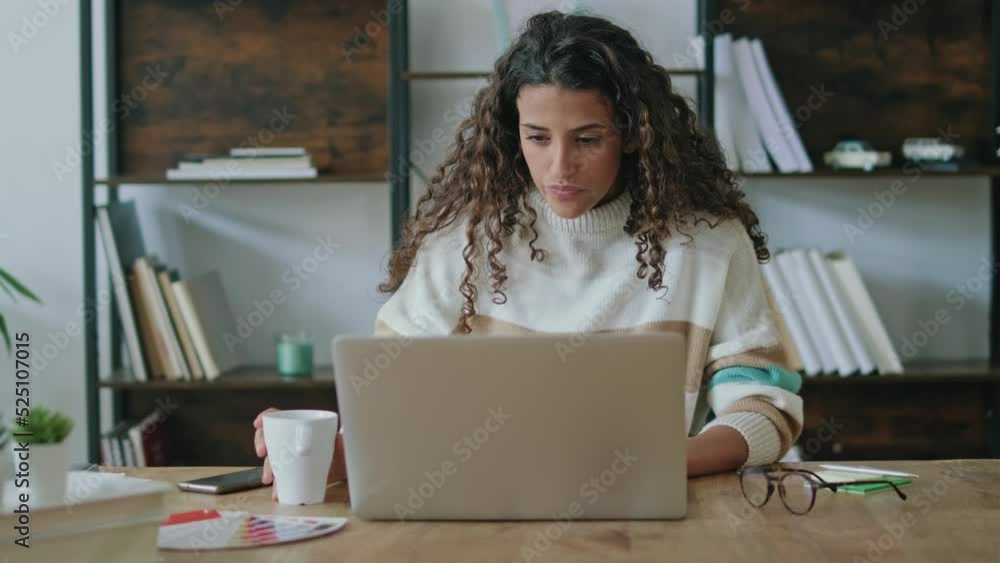 Video of concentrated beautiful business woman working with laptop while drinking coffee in living room at home. Video of concentrated beautiful business woman working with laptop while drinking coffee in living room at home.