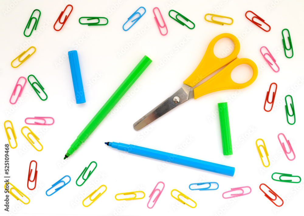 school background wallpaper with paper clips and colored felt-tip pens and scissors close-up on a white background for design school background wallpaper with paper clips and colored felt-tip pens and scissors close-up on a white background for design
