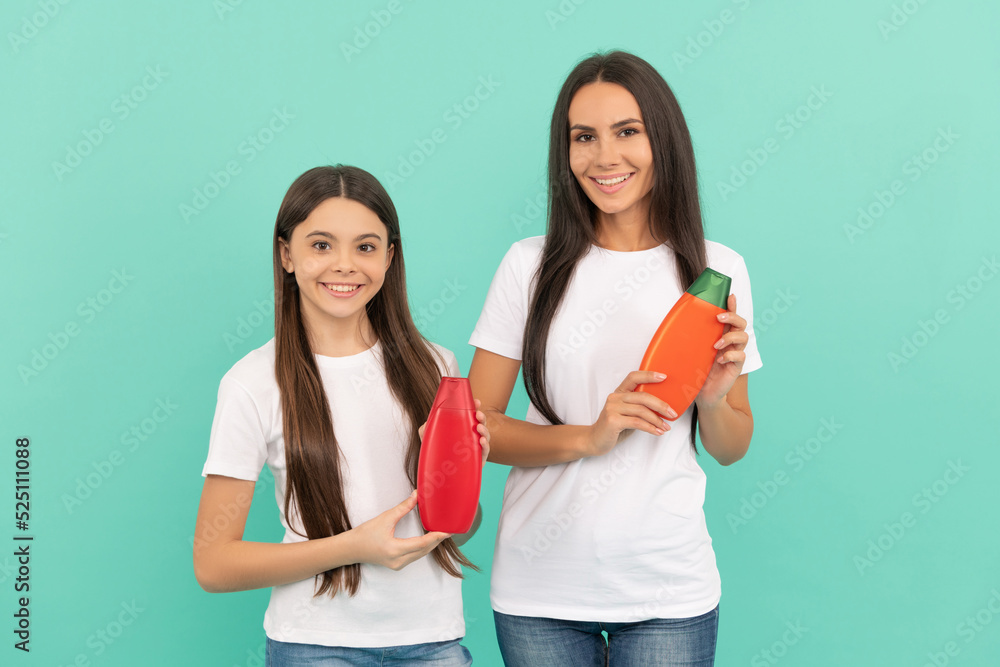 happy mother and daughter hold shampoo bottle on blue background happy mother and daughter hold shampoo bottle on blue background