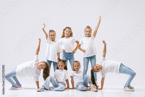 Active little girls, sportive kids in casual style clothes in motion isolated on white studio background. Concept of music, fashion, art, childhood, hobby
