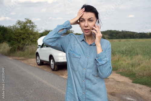 Obraz na płótnie Young upset woman driver standing near the car with the hood opened