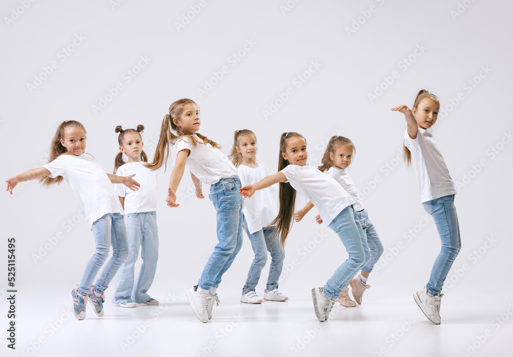 Dance group of happy, active little girls in jeans and t-shirts dancing isolated on white studio background. Concept of music, fashion, art, childhood, hobby Dance group of happy, active little girls in jeans and t-shirts dancing isolated on white studio background. Concept of music, fashion, art, childhood, hobby