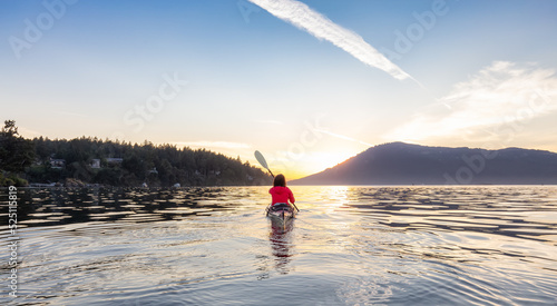 Adventurous Woman on Sea Kayak paddling in the Pacific Ocean. Sunny Summer Sunset. Taken near Victoria, Vancouver Islands, British Columbia, Canada. Concept: Sport, Adventure