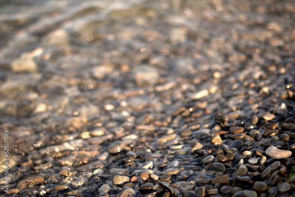 A transparent sea wave rolls over a rocky beach, the concept of rest and travel, calmness and reflection on a warm summer day, defocusing, blurred background, selective focus, bokeh. A transparent sea wave rolls over a rocky beach, the concept of rest and travel, calmness and reflection on a warm summer day, defocusing, blurred background, selective focus, bokeh.