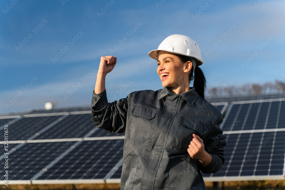 Industrial technician female in white helmet standing in front of the solar panel