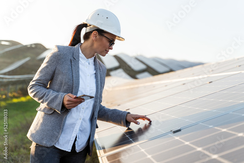 Beautiful Caucasian female technician is looking to the photovoltaic detail in the energy farm