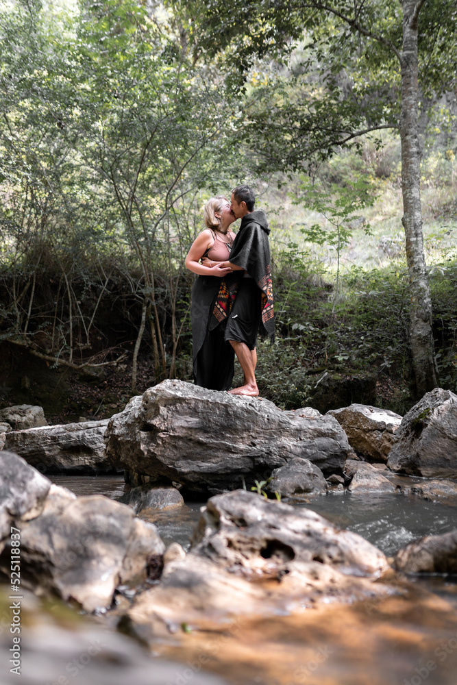 A young couple is kissing on top of a rock barefoot in the river A young couple is kissing on top of a rock barefoot in the river