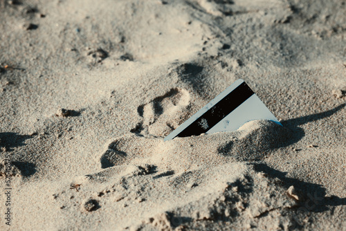 On the beach on the sand one white bank cards. The concept of payment for nature. Copy space.