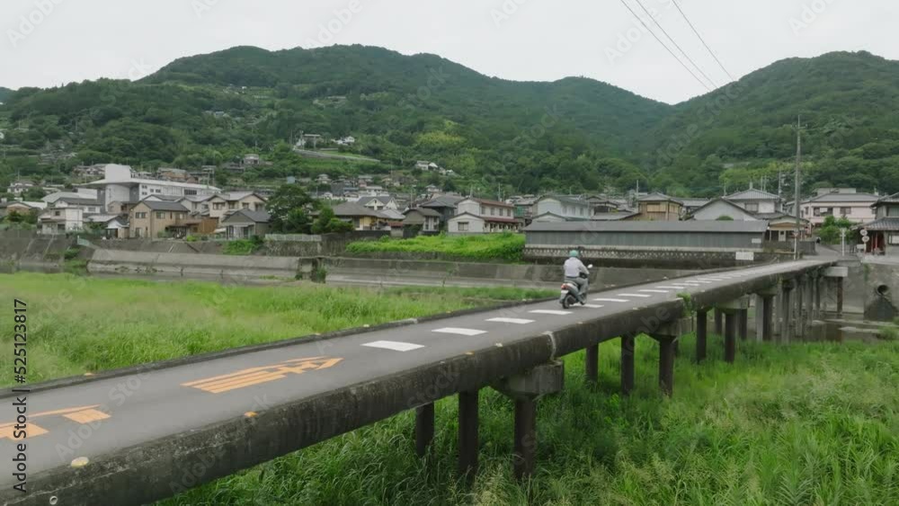 Motorbike crosses narrow bridge with no railing in small rural town Motorbike crosses narrow bridge with no railing in small rural town