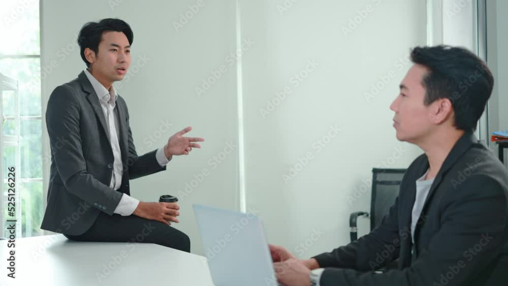 Two Asian business men discuss marketing strategies at the office. business people discuss project planning with friends Two Asian business men discuss marketing strategies at the office. business people discuss project planning with friends