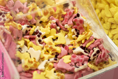Closeup of jelly candy in yellow and pink cow shape in transparent box in confectioner's shop. Low sugar fruit gummies. Smart healthy lifestyle, snacks. Horizontal plane
