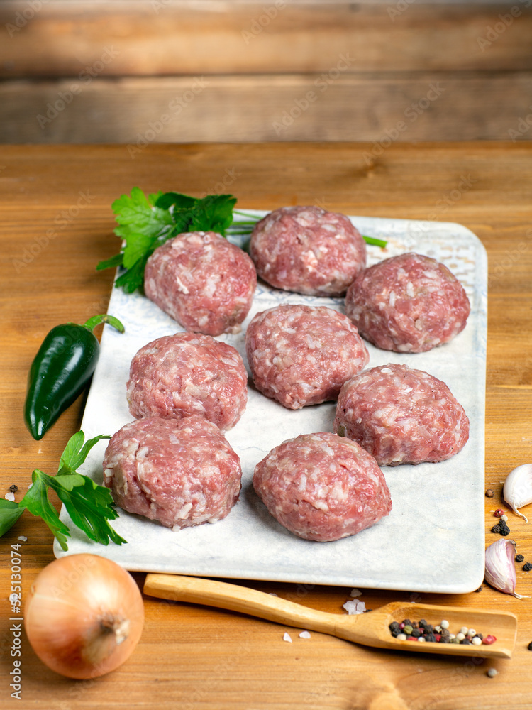 Turkey raw meatballs with vegetables on plate on wooden background. Turkey raw meatballs with vegetables on plate on wooden background.