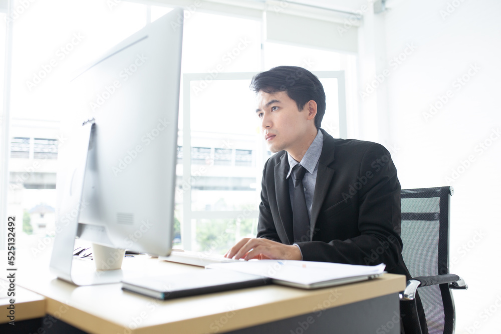 Young businessman working with computer at office. Businessman sitting at office desk working on laptop computer. Young businessman working with computer at office. Businessman sitting at office desk working on laptop computer.