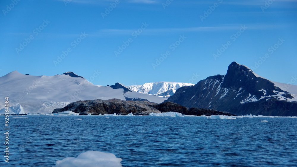 Icebergs floating in the bay, at the base of a snow covered mountain, at Cierva Cove, Antarctica