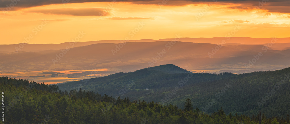 Poland, the Sudetes, mountain landscape in the Snieznik massif, mountain peaks and a valley illuminated by the rays of the setting sun. Poland, the Sudetes, mountain landscape in the Snieznik massif, mountain peaks and a valley illuminated by the rays of the setting sun.