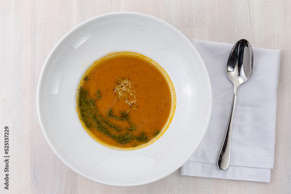 Bowl of carrot soup with microgreens and green oil on the table falt lay Bowl of carrot soup with microgreens and green oil on the table falt lay