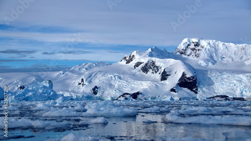 Icebergs floating in the bay, at the base of a snow covered mountain, at Cierva Cove, Antarctica