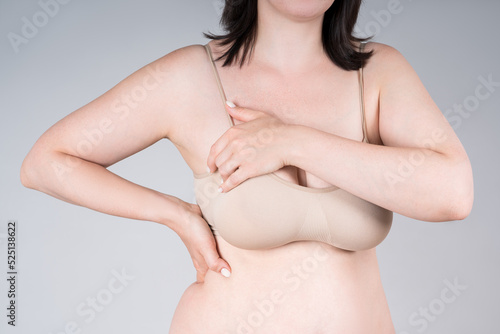 Breast test, woman in beige top bra examining her breasts for cancer on gray background