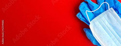 Protective medical mask and disposable gloves on red background