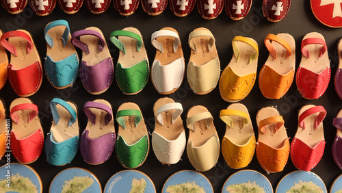 Souvenirs, shaped fridge magnets with small Menorcan avarcas (traditional shoes) - as a symbol of island. Colorful fridge magnets. Selective focus . Ciutadella, Menorca (Minorca), Spain photo