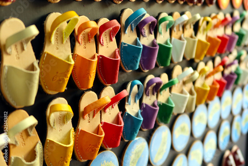 Souvenirs, shaped fridge magnets with small Menorcan avarcas (traditional shoes) - as a symbol of island. Colorful fridge magnets. Selective focus . Ciutadella, Menorca (Minorca), Spain photo