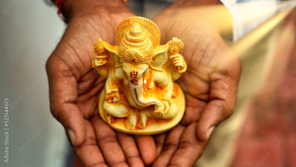Hands holding Lord Ganesha idol in palm background for Visarjan or