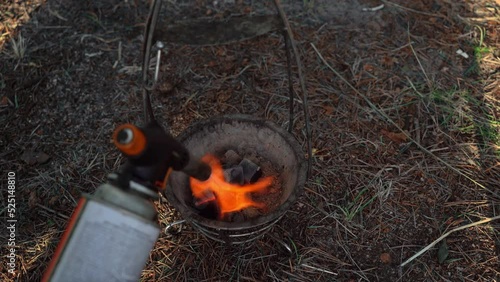 Kindling of coconut coals for a hookah with the gas-burner on nature. Heating the hookah coals. The fire and the smoke. Relax and lounge concepts.