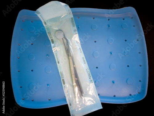Dentist accessories, sterilized and packaged on a blue tray, all on a black background
