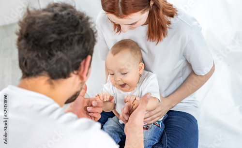dad and mom play with their son. a child in a white t-shirt and blue jeans crawls on the floor. family in studio or at home