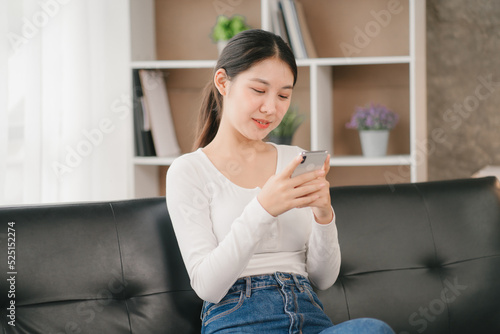 Asian woman happy holding laptop phone sitting sofa smiling good mood indoors indoors