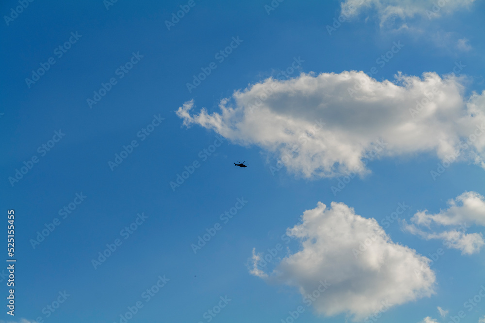Static image of dark helicopter flying over head with blue cloudy sky in the background. High quality photo Static image of dark helicopter flying over head with blue cloudy sky in the background. High quality photo