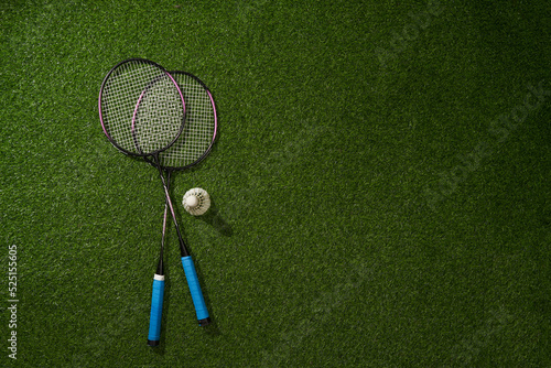 Badminton racket and shuttlecock on green grass background.