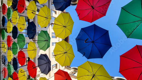 multi color umbrellas as street outdoor decoration, bright blue sky background 