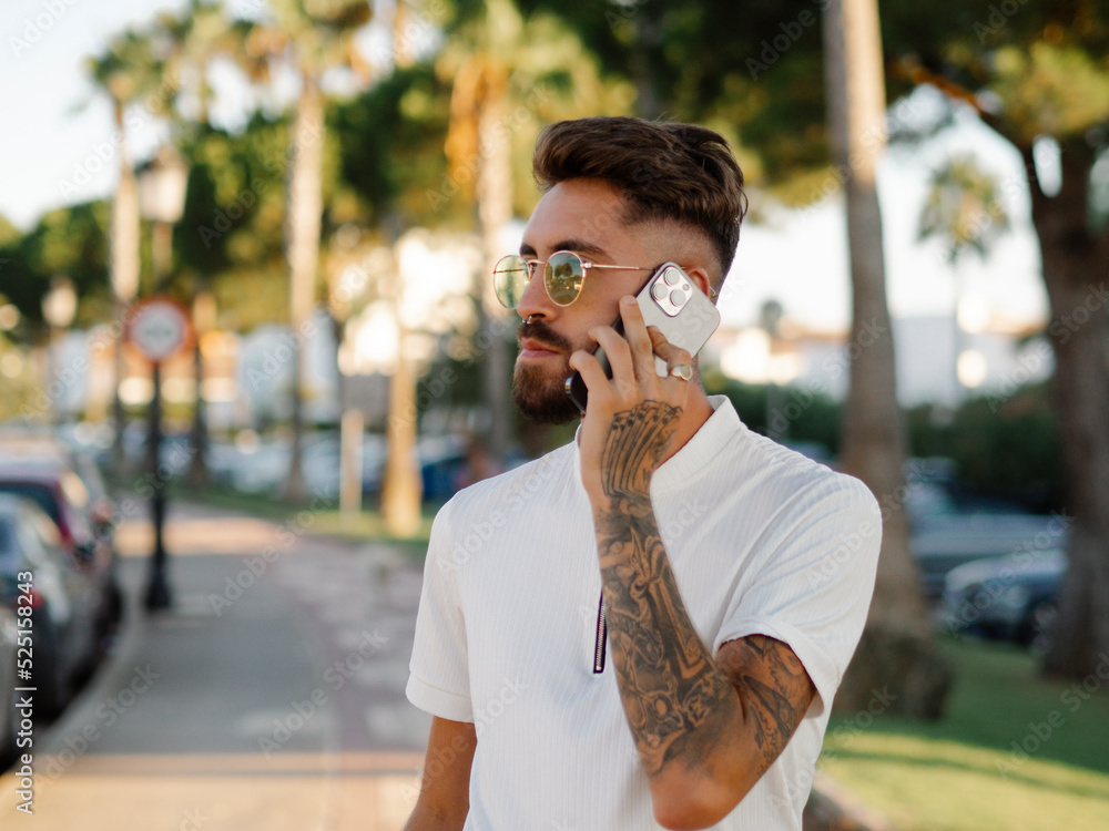 Fototapeta premium Hombre joven con tatuajes usando su teléfono móvil