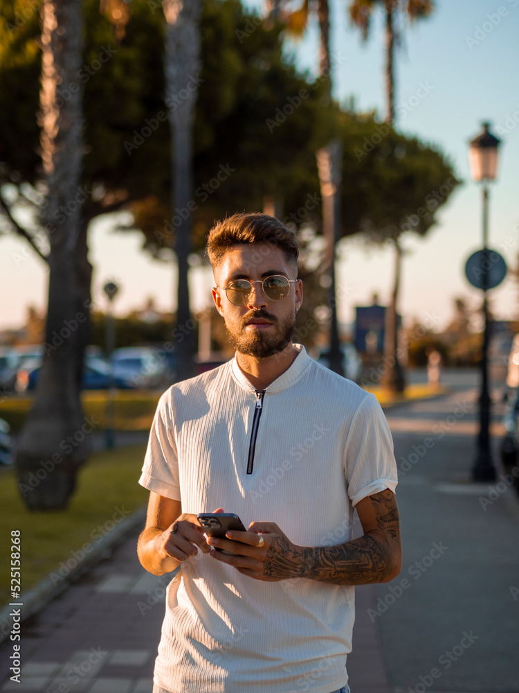 © David Martínez - Hombre joven con tatuajes usando su teléfono móvil © David Martínez - Hombre joven con tatuajes usando su teléfono móvil