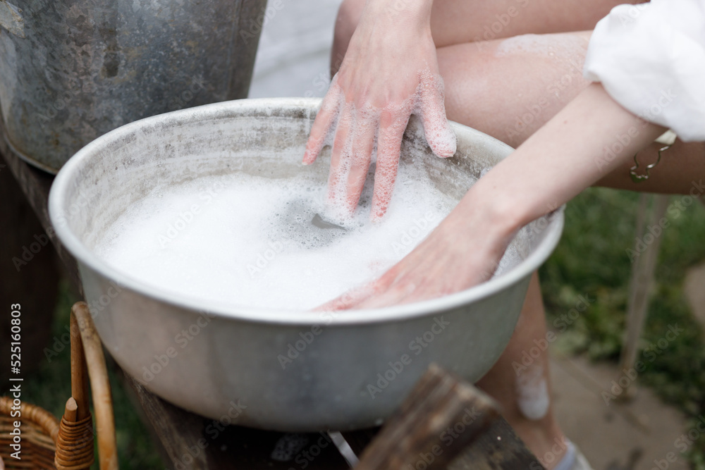 the girl washes in an iron basin in nature. beautiful hands