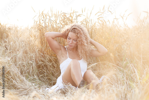 curly-haired girl in the field basking in the sunset sun