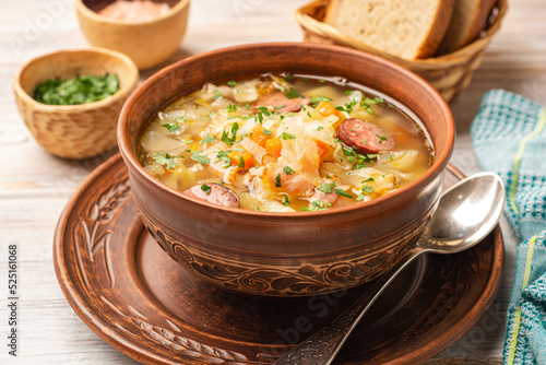 Polish sauerkraut soup Kapusniak in bowl on wooden background