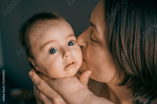 Mom, mummy, young mother with little baby daughter. Mum kissing and hugging child. Newborn cute happy girl smiling in woman hands. Happiness for parents in family. Aged parents, parenting, motherhood