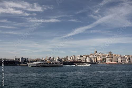 View of a traditional ferry boat and tour boat on Golden Horn part of Bosphorus in Istanbul. Galata tower and Beyoglu district are in the view. It is a sunny summer day. © theendup