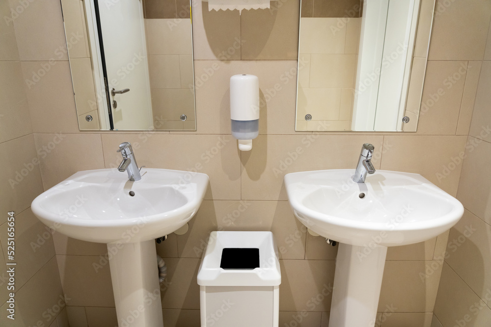 Ceramic sinks in a public toilet with a soap dish and a wastebasket Ceramic sinks in a public toilet with a soap dish and a wastebasket