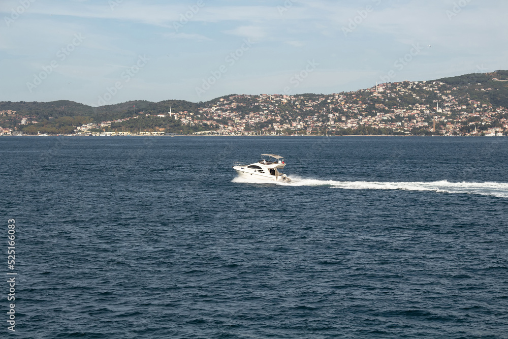 View of a yacht passing on Bosphorus in Istanbul. It is a sunny summer day. Beautiful travel scene.