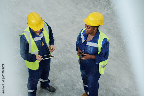 Young male engineer with tablet consulting website to specify technical point while standing in front of female colleague during discussion