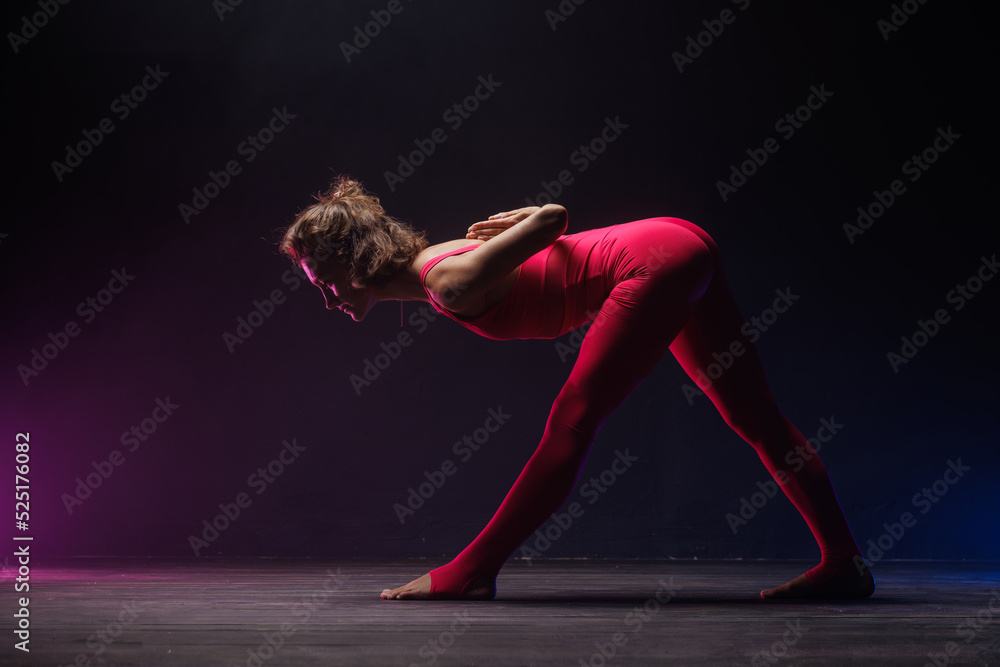 the girl is engaged in stretching on a dark background, a stylish photo of fitness and yoga. Copy space
