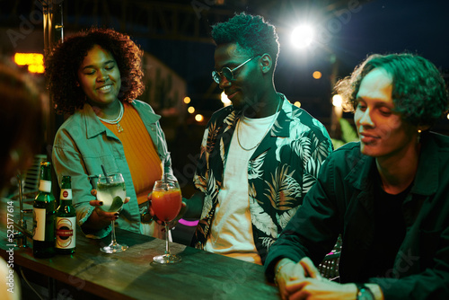 Photography Young man and African American couple with drinks standing by counter while enjo