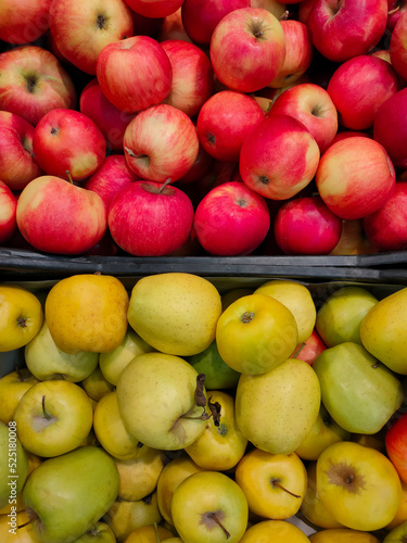 fresh yellow and red apples in plastic boxes on the counter in the supermarket